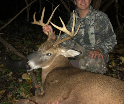 boy posing with buck