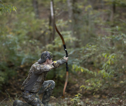 archer shooting arrow in the woods