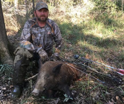 bowhunter posing with hog