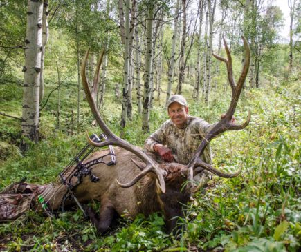 man posing with downed elk