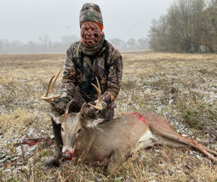 a hunter posing with a downed buck