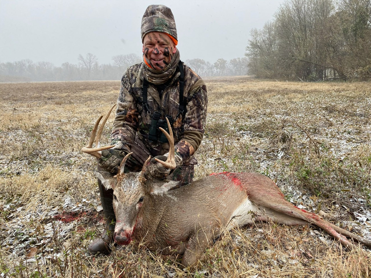 a hunter posing with a downed buck