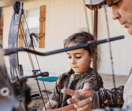 Man showing daughter how to hold a bow