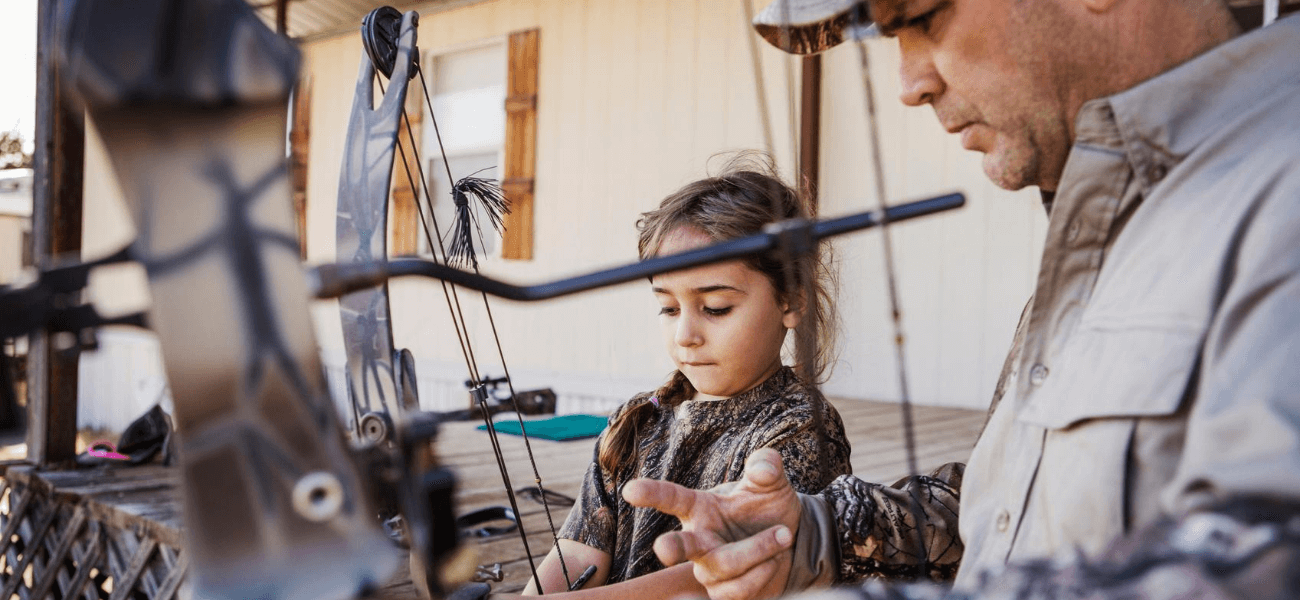 Man showing daughter how to hold a bow