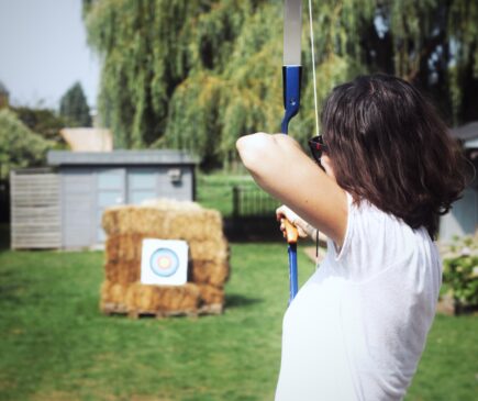 a woman shooting a bow in a backyard archery