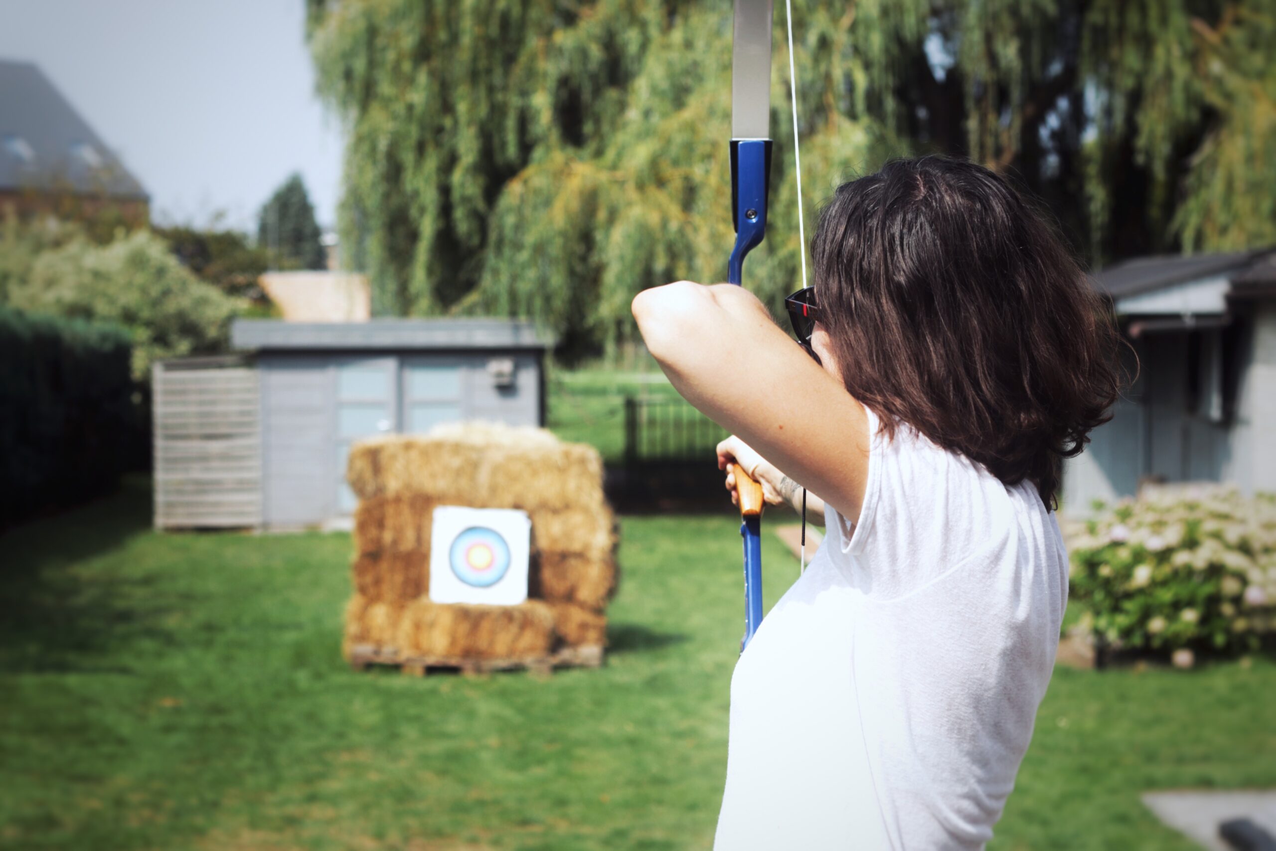a woman shooting a bow in a backyard archery